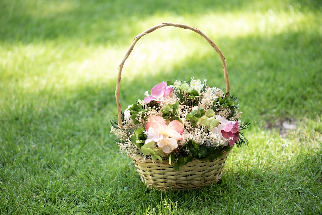 Vibrant floral basket displayed outdoors on green grass in bright sunlight, perfect for nature themes.