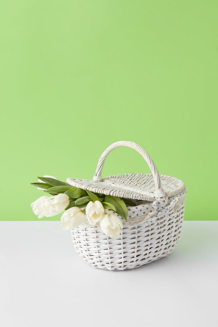 White wicker basket with fresh tulips against a vibrant green background.